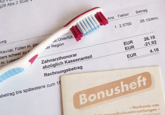 Bonusheft in der Zahnarztpraxis mit Zahnbürste abgebildet auf einen Kostenvoranschlag liegend.